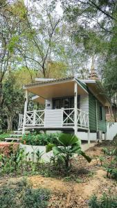 una pequeña casa verde y blanca con porche en Dara Express Inn by Angkor Green Gardens, en Phumĭ Thnál