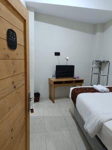 a bedroom with a bed and a desk with a television at Jogja Amor Hotel in Demangan