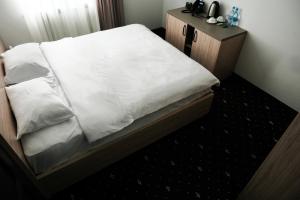 ein Bett mit weißer Bettwäsche und einem hölzernen Nachttisch in der Unterkunft Colette Hotel in Yerevan