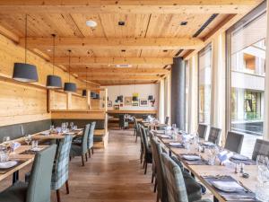 a dining room with wooden ceilings and tables and chairs at Falkensteiner Hotel Schladming in Schladming