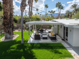 an outdoor patio with palm trees and grass at R & R Rendezvous in Palm Springs