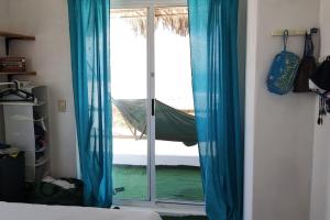 a bedroom with blue curtains and a sliding glass door at Casita de renta frente la playa in San Juanico