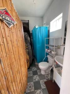 a bathroom with a bamboo shower curtain and a toilet at Casita de renta frente la playa in San Juanico