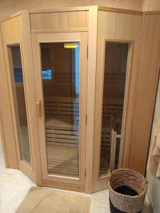 a wooden cabinet with glass doors in a room at jolie maison neuve - malisone - in Pont-Sainte-Maxence