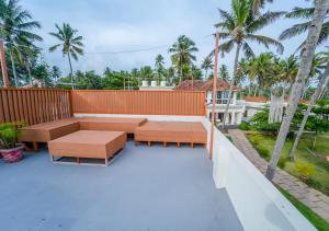 a patio with benches and a fence and palm trees at Solaris Varkala Beach Resort By VOYE HOMES in Varkala
