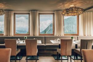 ein Restaurant mit Tischen, Stühlen und Fenstern in der Unterkunft Falkensteiner Family Hotel Sonnenalpe in Sonnenalpe Nassfeld
