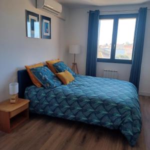 een slaapkamer met een bed met een blauw dekbed en een raam bij St Loup in Bessan