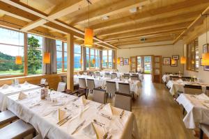 ein Restaurant mit weißen Tischen, Stühlen und Fenstern in der Unterkunft Falkensteiner Aktiv & Familienhotel Cristallo in Katschberghöhe