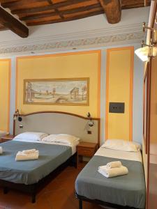 2 camas en una habitación con paredes amarillas en San Pietro Tuscany Suites, en Lucca