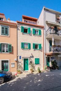 a building with green shutters and a car parked in front at Central Split rooms and apartments Paese in Split