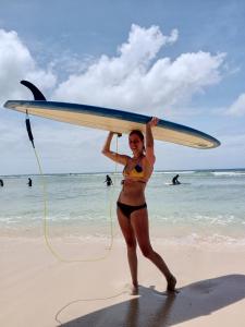 a woman in a bikini holding a surfboard on the beach at sharkbunkbed siargao in General Luna