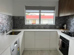 a white kitchen with a sink and a window at Private Room in Kawakawa