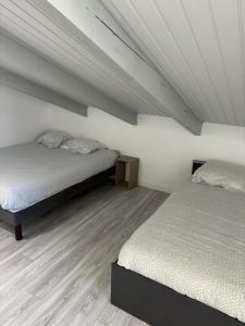Lou Castel في Pomérols: سريرين في غرفة بجدران بيضاء وأرضية خشبية