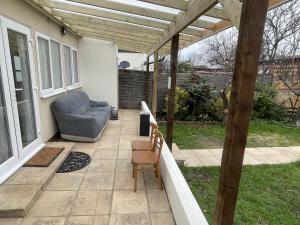 a patio with a couch and a chair under a pergola at Spacious one bedroom apartment with free parking in Enfield