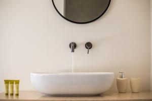 La salle de bains est pourvue d'un lavabo blanc et d'un miroir. dans l'établissement Aethrion Villas & Suites, à Gennadi