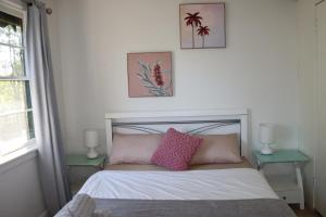 1 dormitorio con 1 cama con almohadas rosas y 2 mesas en Humble Abode near Ringwood, en Heathmont