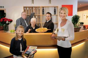 Una donna che tiene un vassoio di pizza con una ragazza di EWERTS Hotel a Netphen