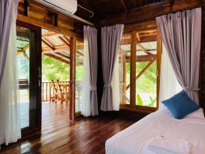 a bedroom with a bed in a room with windows at บ้านสวนแก้วคำแพง Baan Suan Kaew Khampaeng in Udon Thani