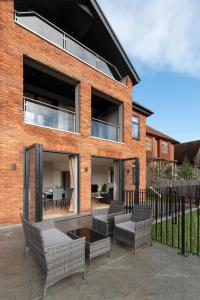 a brick house with a patio with chairs and a table at Modern Two Bedrooms Flat in Julien Road, CR5, London in Coulsdon
