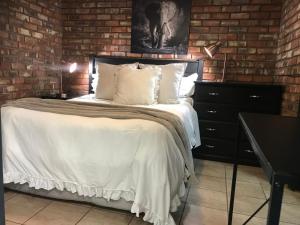 ein Schlafzimmer mit einem Bett und einer Ziegelwand in der Unterkunft Aloe Klerksdorp in Klerksdorp