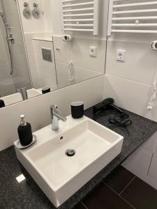 La salle de bains est pourvue d'un lavabo blanc et d'un miroir. dans l'établissement Cozy Modern Studio Next to Easy Side Galley, à Berlin