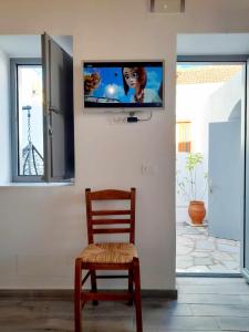 a television on a wall with a wooden chair at ZEUS HOUSE in Symi