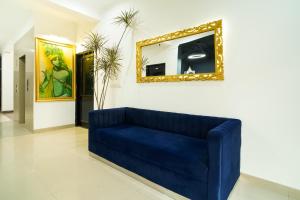 Sofá azul en la sala de estar con espejo en Cozy Inn en Gurgaon