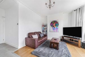 a living room with a couch and a flat screen tv at Bright West Ealing Abode in Hanwell