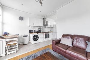 a living room with a couch and a kitchen at Bright West Ealing Abode in Hanwell
