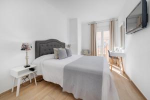 a white bedroom with a bed and a tv at Hotel Madrid in Torrevieja +224 photos
