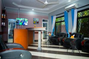 una sala de espera con sillas, una mesa y un bar en Magdon Executive Lodge en Dar es Salaam