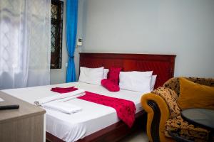 um quarto com uma cama com almofadas vermelhas e uma cadeira em Magdon Executive Lodge em Dar es Salaam