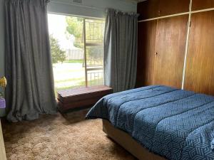 a bedroom with a bed and a large window at Kharimbi Camp House in Brakpan