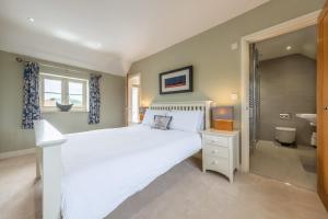 バーナム・マーケットにあるGuardian Houseの白いベッドとバスルームのある寝室