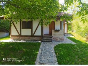 a small house with a tree and a walkway at Vodenica Lug in Strmosten