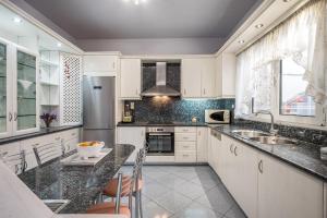una cucina con armadi bianchi e ripiani in granito di apartment a Heraklion