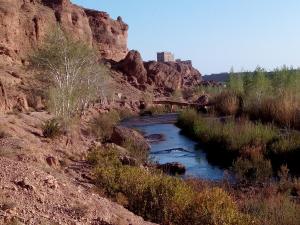 einem Fluss in der Mitte eines Canyon mit einer Brücke in der Unterkunft KASBAH ALTAÏR in El-Kelâa M’Gouna
