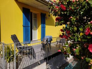 a yellow house with blue shutters and chairs on a balcony at Dolceresio Lugano Lake B&B in Brusino Arsizio