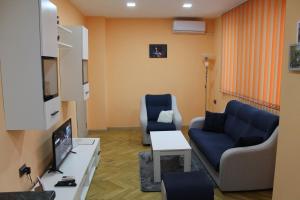 sala de estar con 2 sillas azules y TV en Апартамент за нощувка, център!, en Stara Zagora