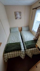 twee bedden in een kleine kamer met een raam bij SKYLA VISTA Clacton-on-Sea in Clacton-on-Sea