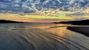 a view of a beach with a sunset in the background at John Eoinìn's Bar and accommodation in Glencolumbkille