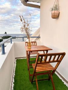 uma mesa e cadeira de madeira numa varanda com relva verde em Duplex Ophélie em Saint-Denis