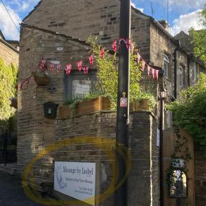 a house with a sign in front of it at The Therapy Rooms Holmfirth Holiday Let in Holmfirth