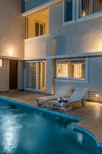 a house with a swimming pool with two lounge chairs at ELIVAAS Shourya Eden Luxe 3BHK Villa with Pvt Pool, Udaipur in Udaipur