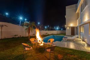 a backyard with a fire pit and a pool at night at ELIVAAS Shourya Eden Luxe 3BHK Villa with Pvt Pool, Udaipur in Udaipur +35 photos