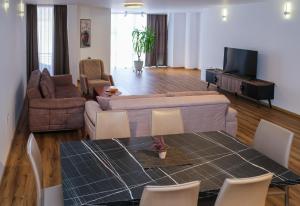 uma sala de estar com um sofá, uma mesa e cadeiras em Nest Apartments em Gjakove