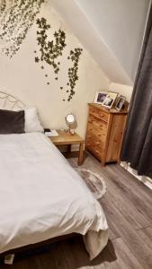 een slaapkamer met een wit bed en een houten dressoir bij PEACEFULLY AND CENTRALLY LOCATED DOUBLE BEDROOM in Hunslet