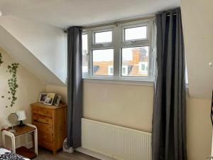 een slaapkamer met een raam, een dressoir en een bed bij PEACEFULLY AND CENTRALLY LOCATED DOUBLE BEDROOM in Hunslet