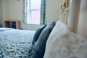 een slaapkamer met een bed met blauwe kussens en een raam bij PEACEFULLY AND CENTRALLY LOCATED DOUBLE BEDROOM in Hunslet