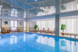 a large swimming pool in a building with chairs at Shera Inn Hotel in Almaty